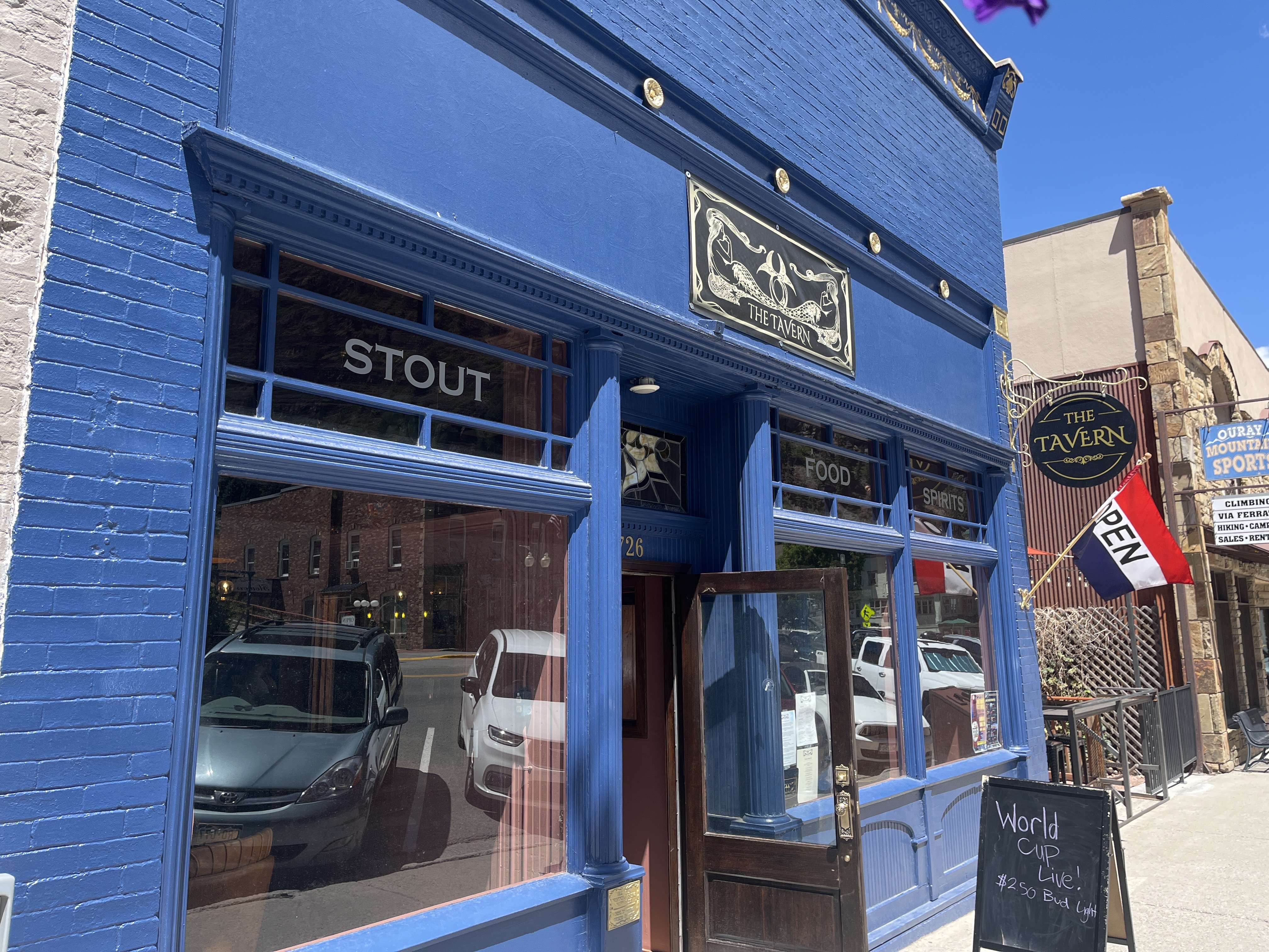 The Tavern blue facade at 726 Main Street, Ouray — STOUT, FOOD, SPIRITS in the windows.