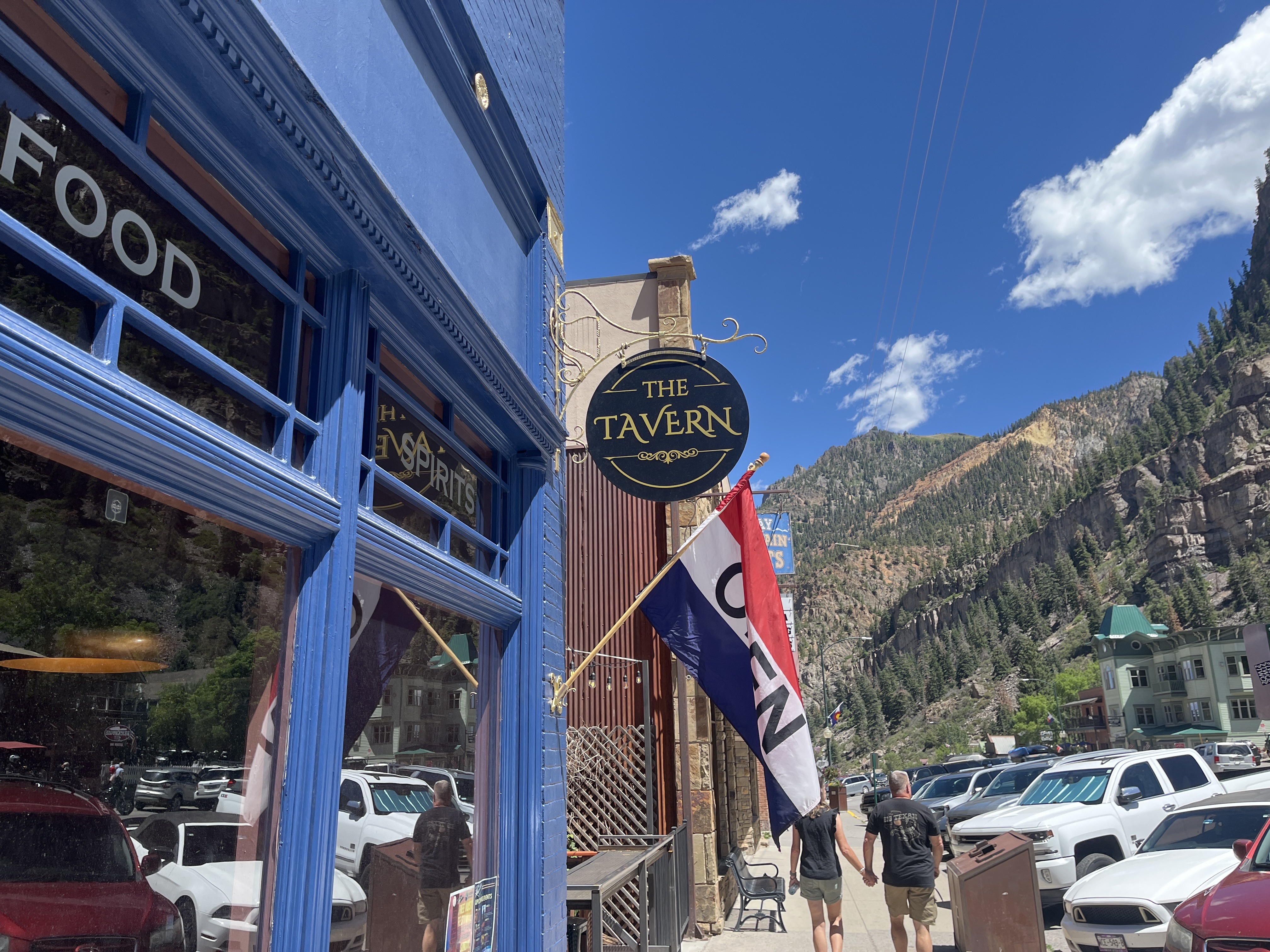 The Tavern's hanging sign at 726 Main Street with the San Juan Mountains rising behind.