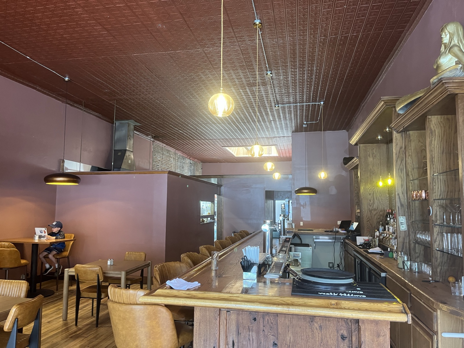 The Tavern bar room — long wood bar, pressed-tin ceiling and warm pendant lighting.